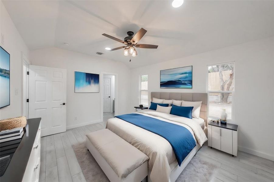 Bedroom with multiple windows, vaulted ceiling, ceiling fan, and light hardwood / wood-style flooring