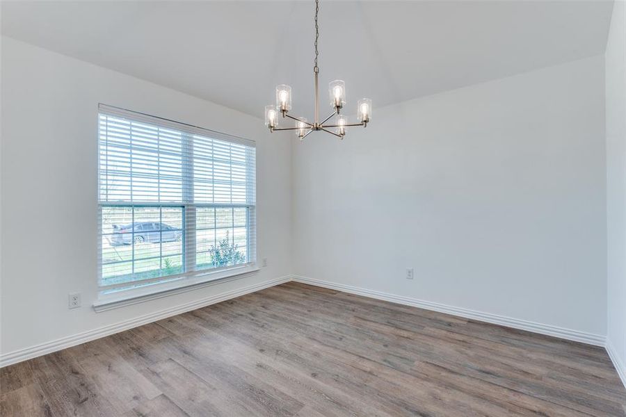 Spare room with a notable chandelier, vaulted ceiling, and hardwood / wood-style flooring