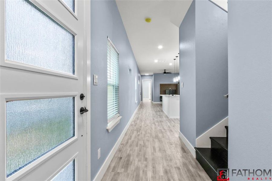 Corridor with light hardwood / wood-style flooring and a healthy amount of sunlight