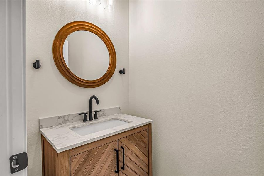 First floor power room with stained wood vanity and coordinating mirror.