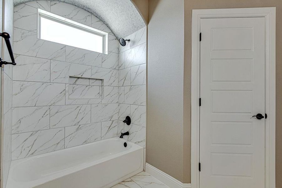 Bathroom featuring tiled shower / bath combo and tile patterned flooring