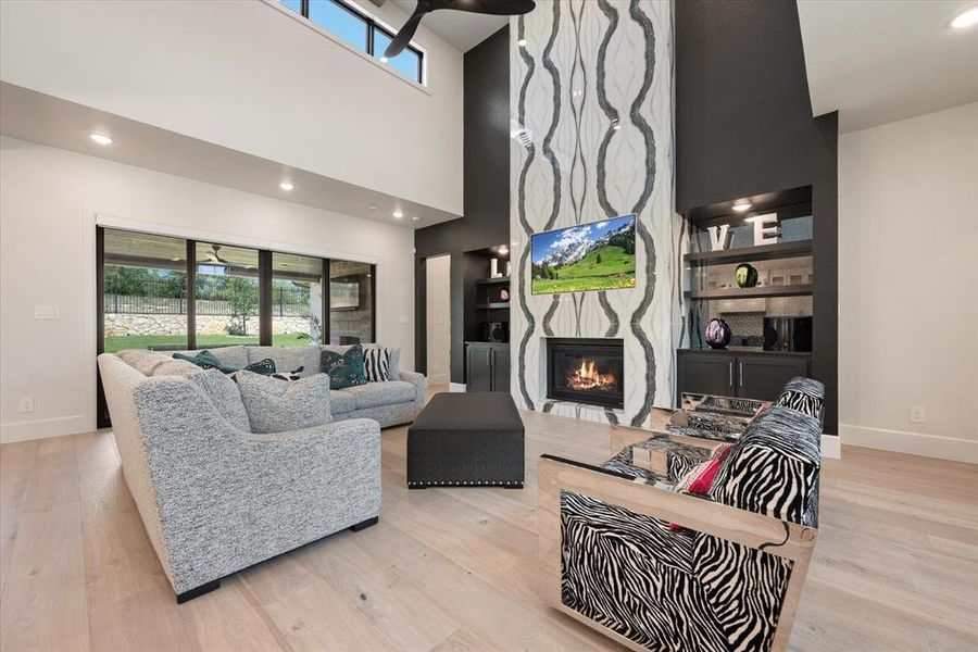 Living room with plenty of natural light, a high ceiling, a large fireplace, and light hardwood / wood-style floors