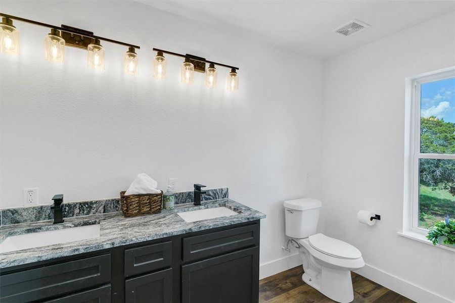 Bathroom featuring hardwood / wood-style floors, dual vanity, and toilet