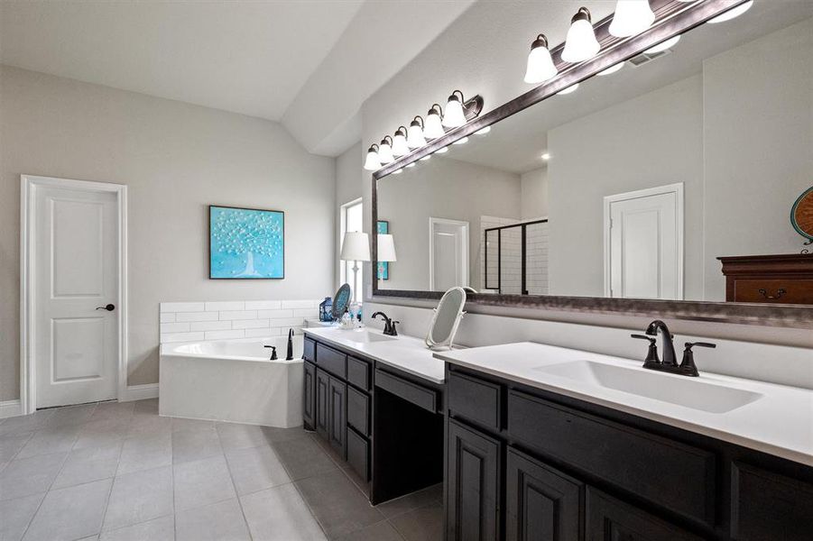 Bathroom with tile floors, a bath to relax in, and double sink vanity