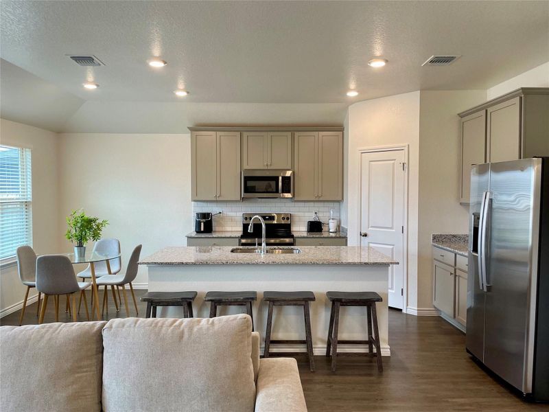 Granite counters and stainless appliances in this open kitchen.