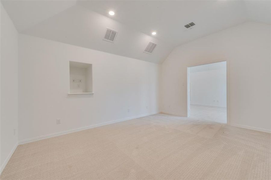 Empty room featuring vaulted ceiling and light colored carpet