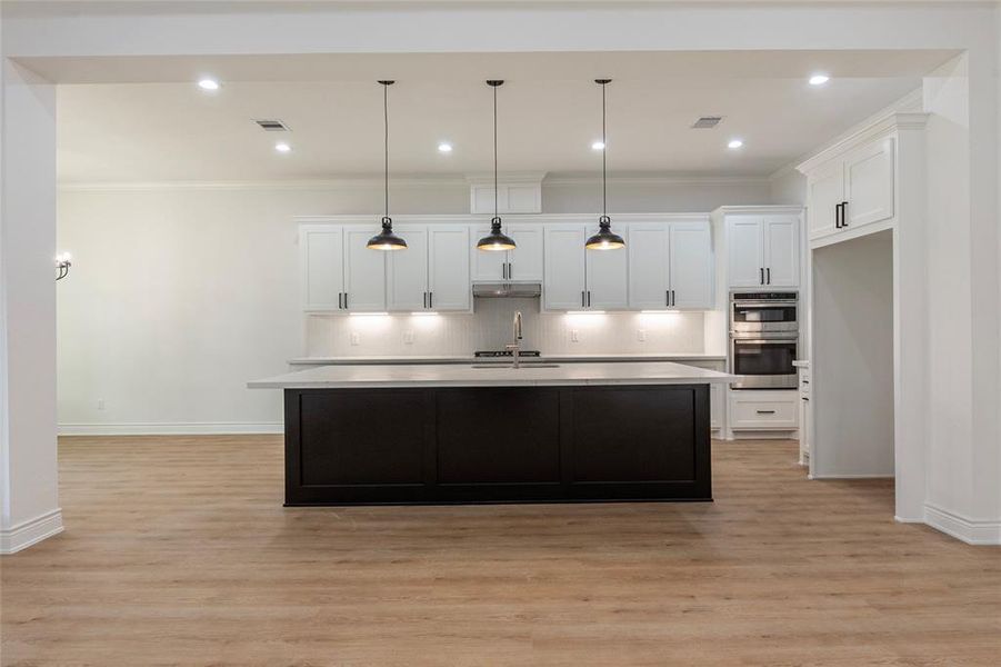 The kitchen island is accented with modern pendant lighting.