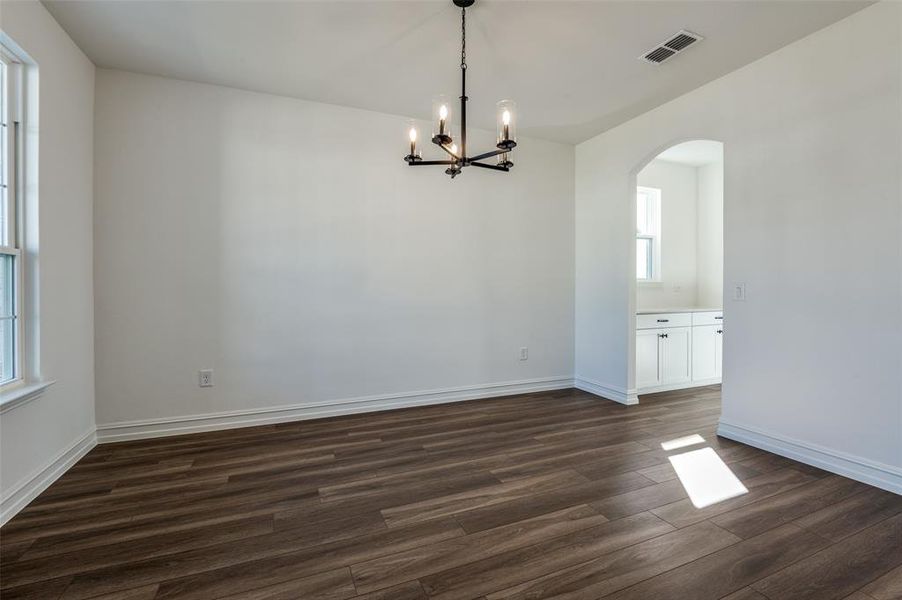 Unfurnished room featuring a notable chandelier and dark hardwood / wood-style flooring