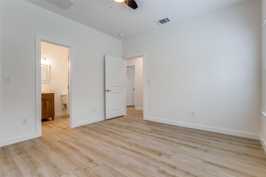 Primary bedroom featuring connected bathroom, clsoet, light wood-type flooring, and ceiling fan