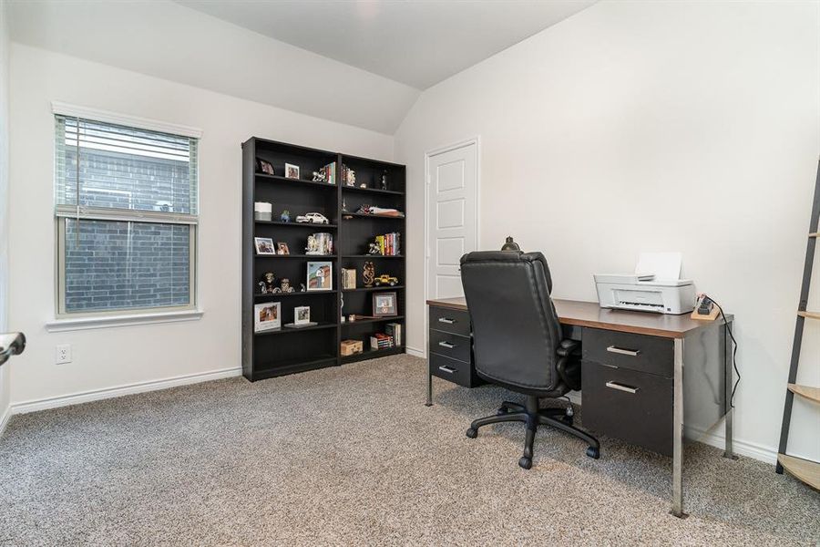 Carpeted home office featuring vaulted ceiling