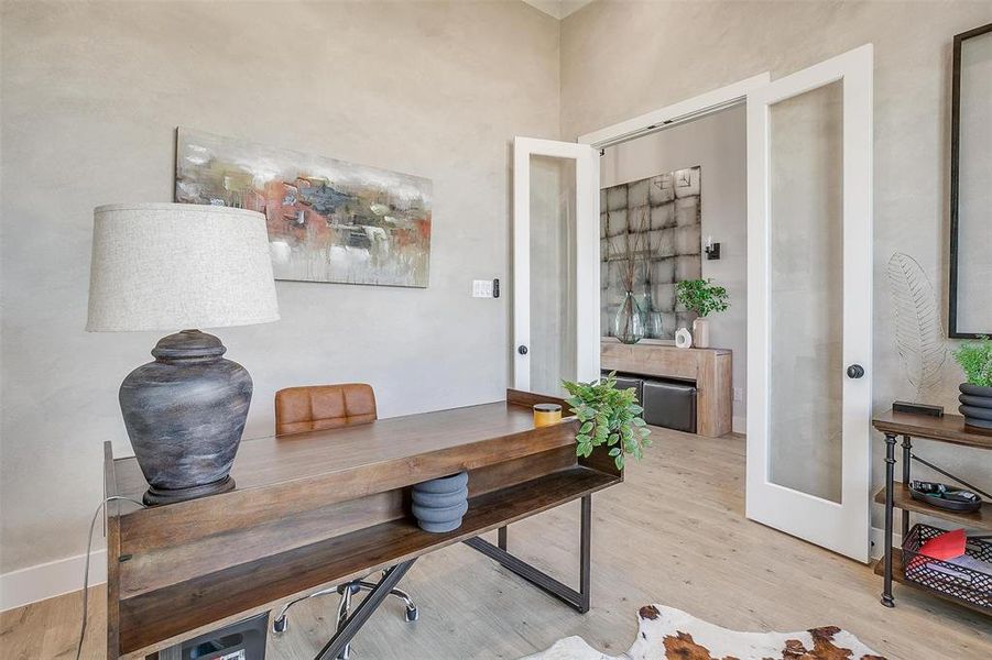 Office with light hardwood / wood-style flooring and french doors