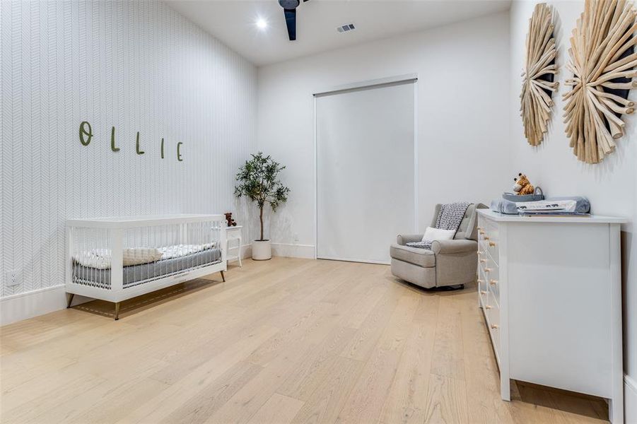 Bedroom with a crib and light hardwood / wood-style flooring