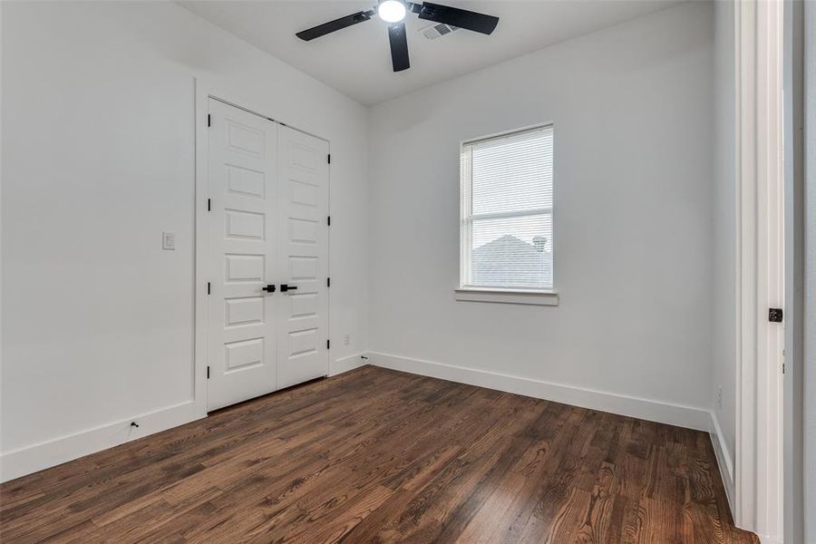 Secondary bedroom with ceiling fan and hardwood floors.