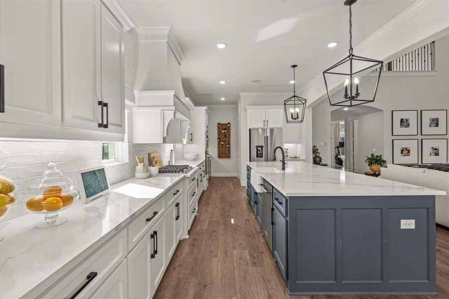 Kitchen with hanging light fixtures, white cabinetry, stainless steel appliances, dark wood-type flooring, and ornamental molding