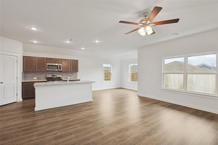 Kitchen featuring appliances with stainless steel finishes, a kitchen island with sink, backsplash, and dark hardwood / wood-style flooring