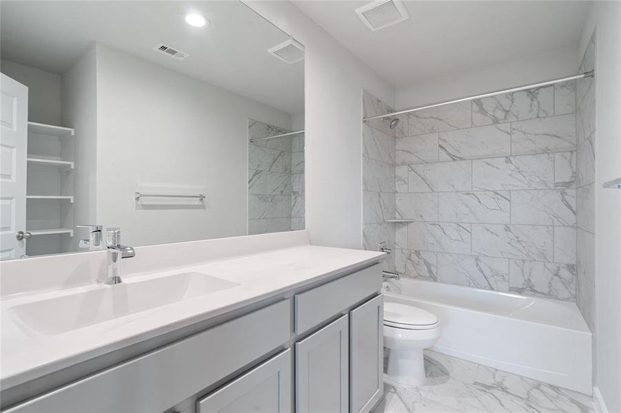 Secondary bath features tile flooring, bath/shower combo with tile surround, light wood cabinets, beautiful light countertops, mirror, sleek fixtures and modern finishes!