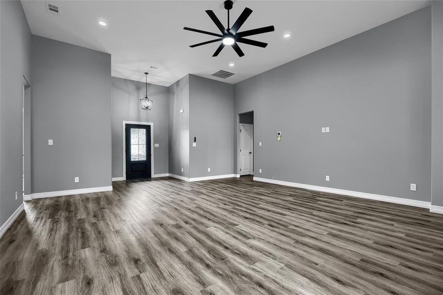 Unfurnished living room with dark hardwood / wood-style floors, ceiling fan, and a towering ceiling