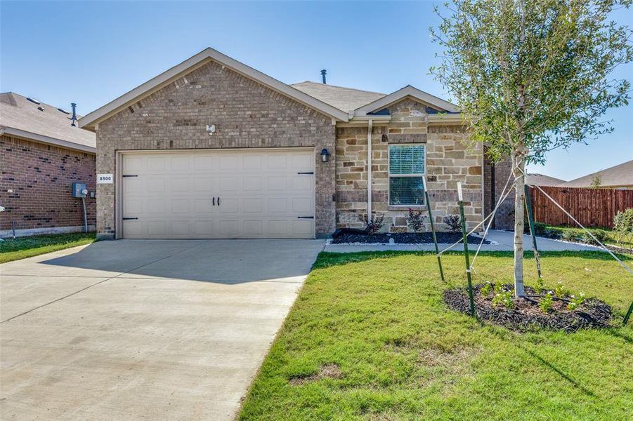 Ranch-style home featuring a garage and a front lawn