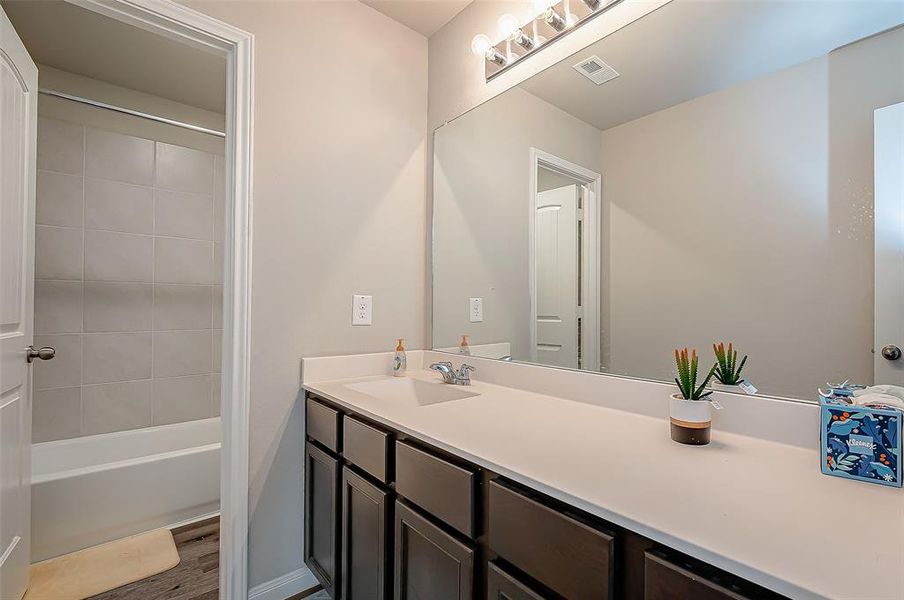 The vanity area in the secondary bathroom features a large mirror with warm lighting.