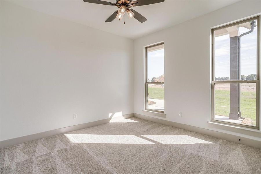 Carpeted empty room with ceiling fan and a wealth of natural light