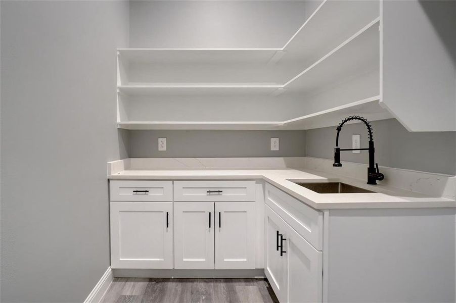 Kitchen with sink, white cabinetry, and hardwood / wood-style flooring