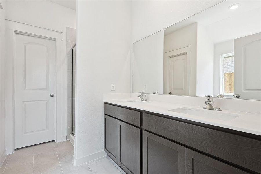 Bathroom with tile patterned floors, a shower with door, and vanity