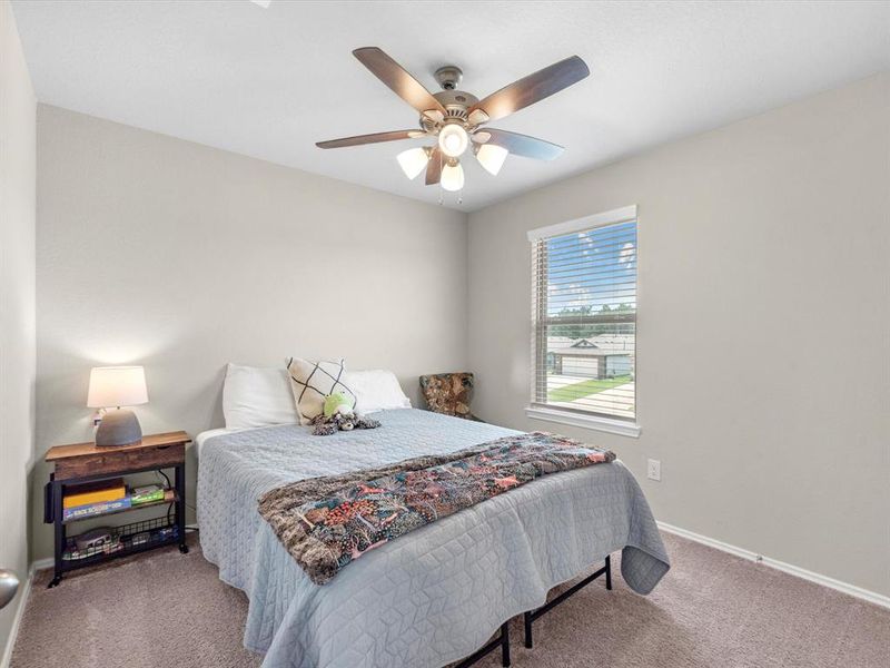 Your secondary bedroom features plush carpet, fresh paint, ceiling fan with lighting, and a large window with privacy shades.
