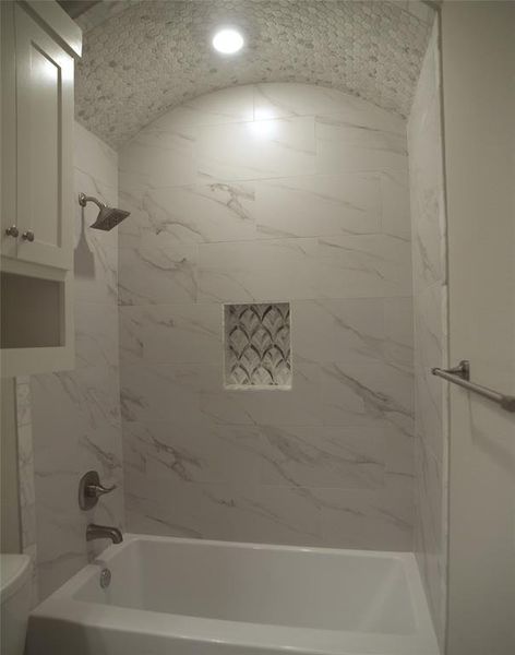 Bathroom featuring tiled shower / bath combo and toilet