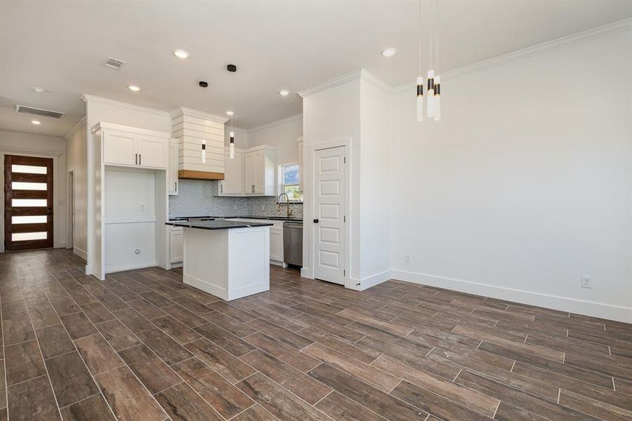 Kitchen featuring white cabinets, hanging light fixtures, dark hardwood / wood-style floors, and a kitchen island