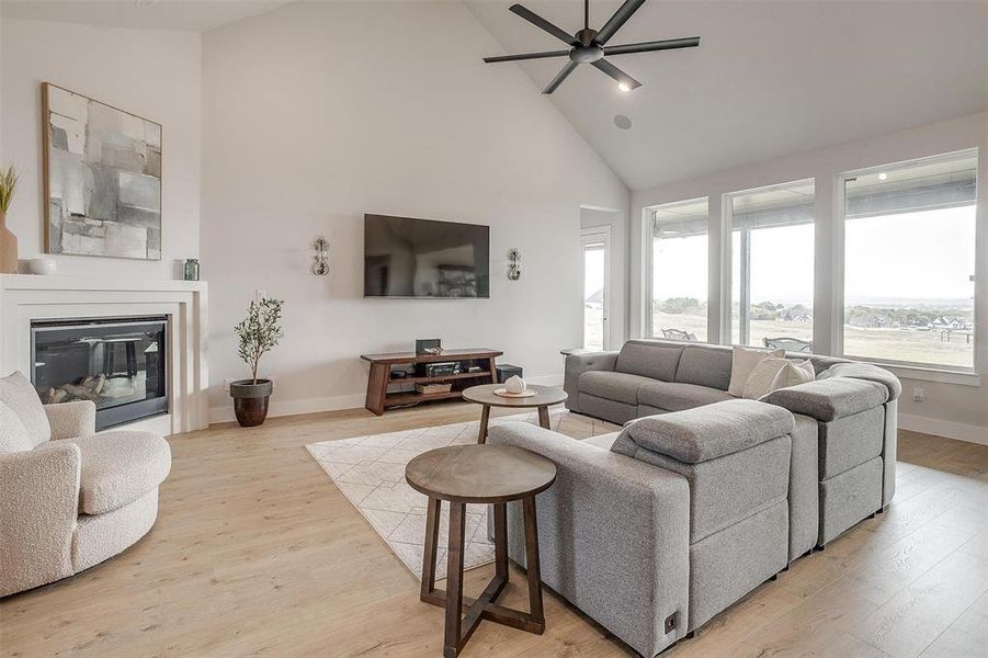 Living room with high vaulted ceiling, light hardwood / wood-style floors, and ceiling fan