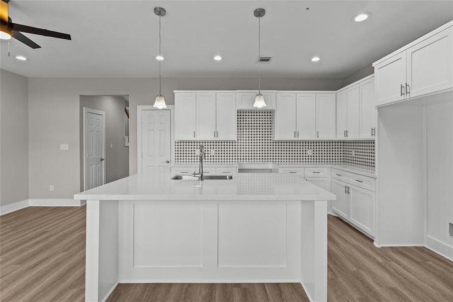 Sleek and modern, the kitchen features a large island, elegant backsplash, and recessed lighting for a fresh, contemporary feel.