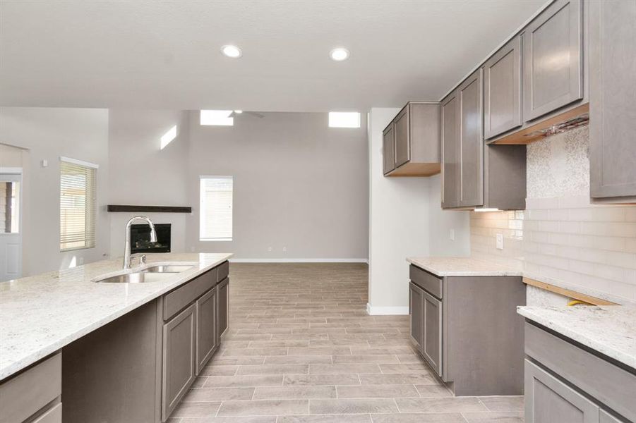 Discover another perspective of this stunning kitchen, generously appointed with an abundance of counter space and seemlessly connected to the family room. Sample photo of completed home with similar floor plan. As-built interior colors and selections may vary.