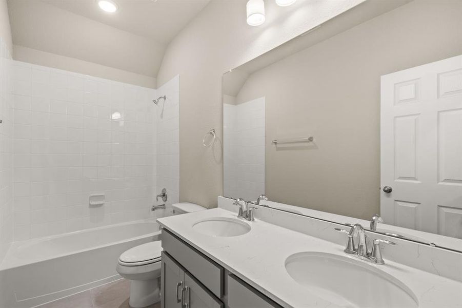 The secondary bath features tile flooring, white cabinetry and light countertops and a shower/tub combo. Perfect for accommodating any visiting family and friends.