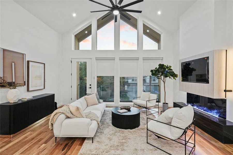 Living room with light hardwood / wood-style flooring, ceiling fan, and high vaulted ceiling