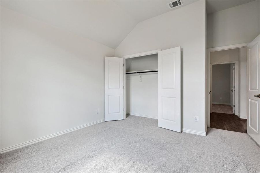 Unfurnished bedroom with high vaulted ceiling, a closet, and carpet