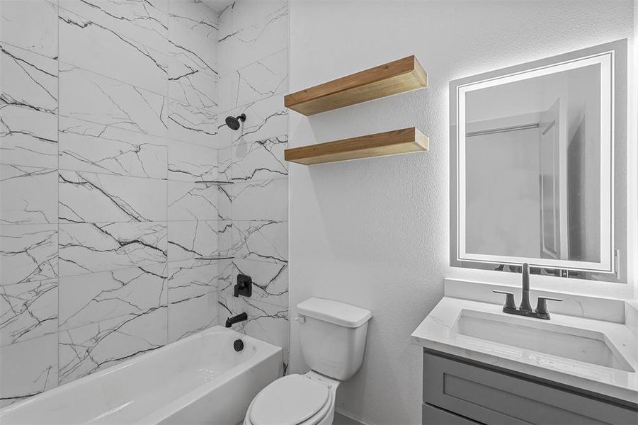 Full bathroom featuring tiled shower / bath combo, vanity, and toilet