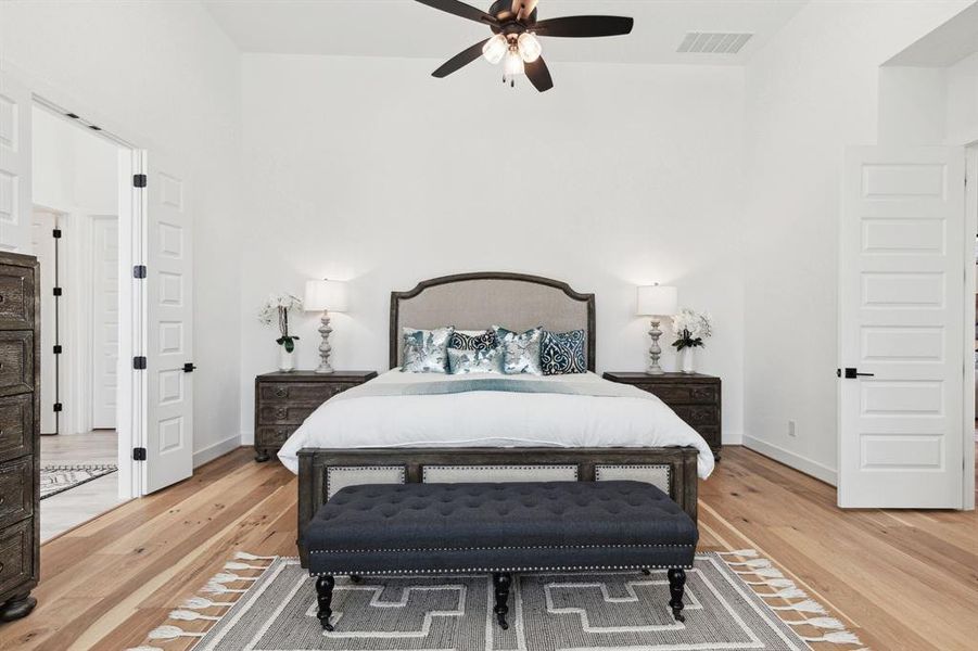 Oversized with high ceilings, the primary bedroom accommodates large furniture, while the wood floors bring forth a cozy and comfortable vibe.