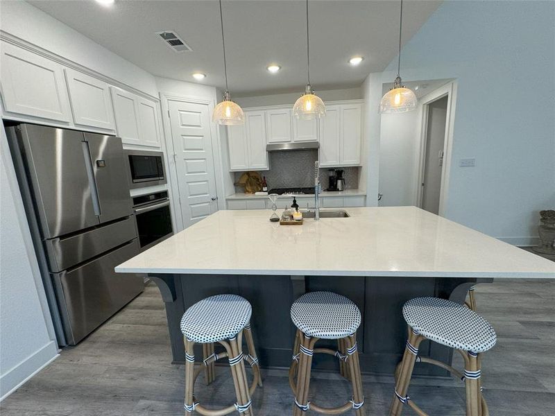 Kitchen with appliances with stainless steel finishes, white cabinetry, and a large island