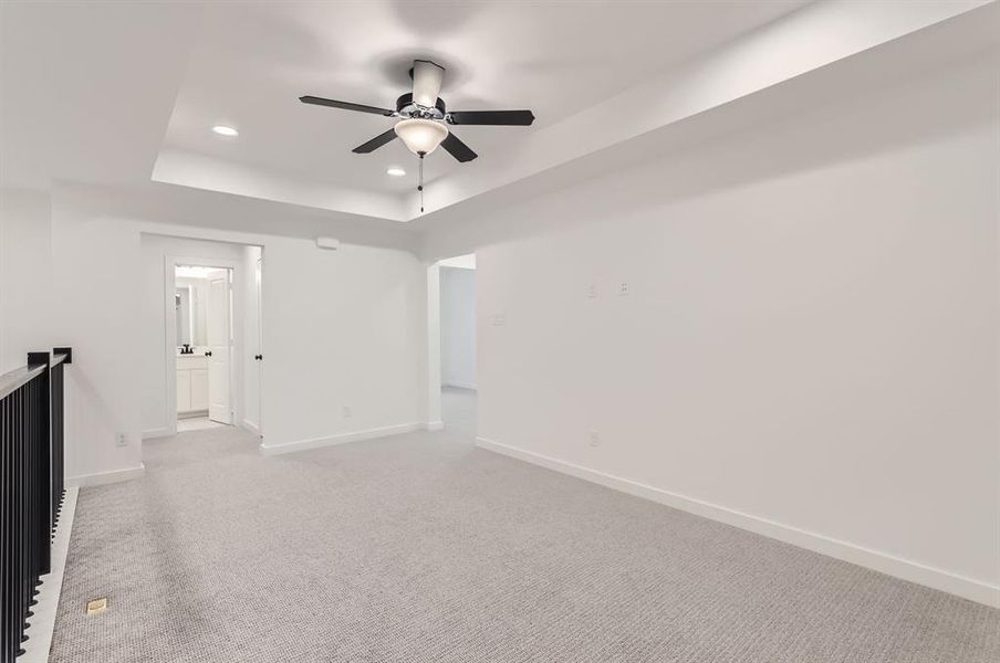 Spare room featuring ceiling fan, a tray ceiling, and light colored carpet