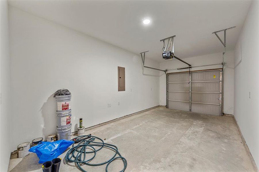 Garage featuring electric panel and a garage door opener