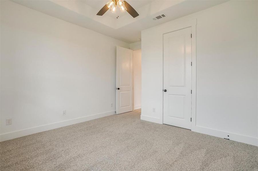 Unfurnished bedroom with ceiling fan and light carpet