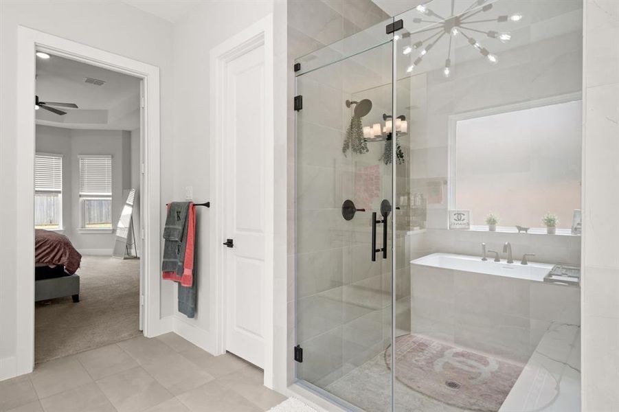 The primary bathroom showcases a spacious tiled walk-in shower and stylish tile flooring, offering a contemporary and functional bathing space.