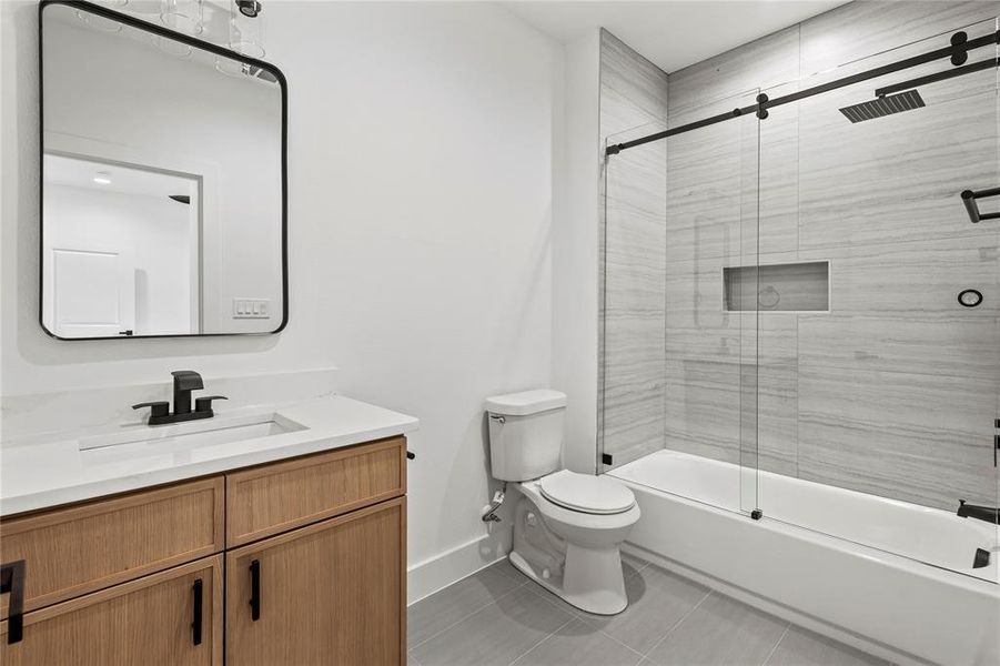 Full bathroom featuring tile floors, bath / shower combo with glass door, vanity, and toilet