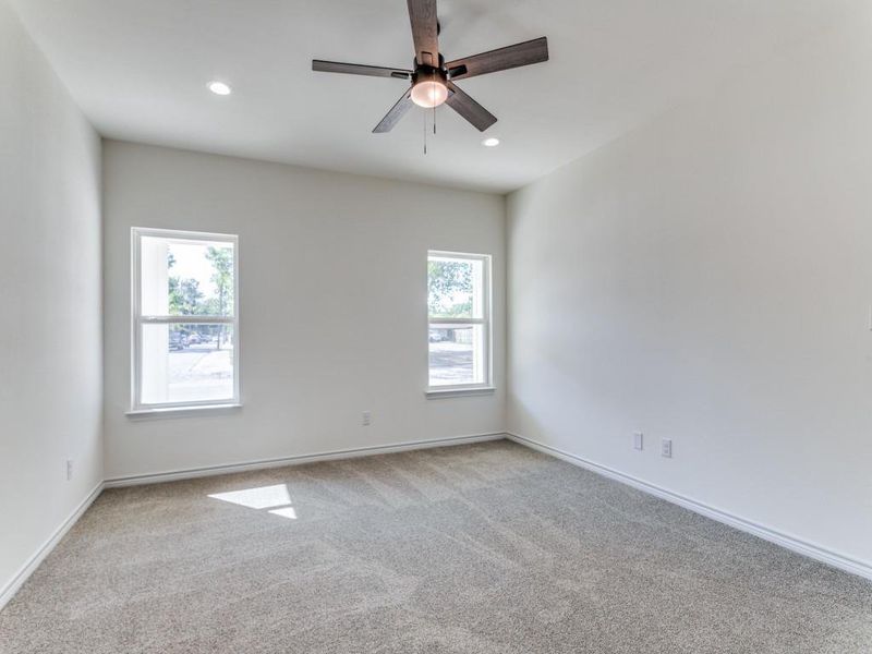 Carpeted spare room with a healthy amount of sunlight and ceiling fan