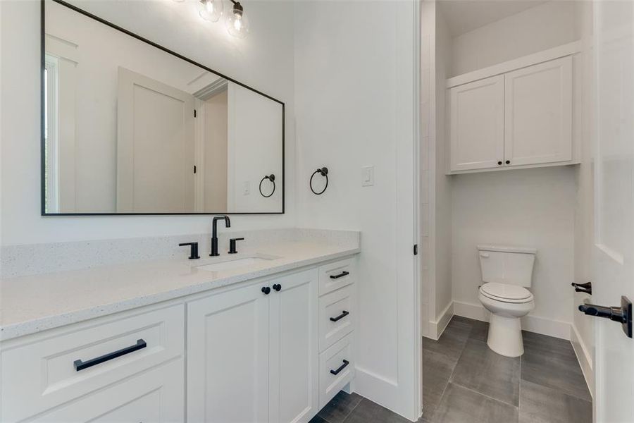 Bathroom featuring tile patterned flooring, toilet, and vanity