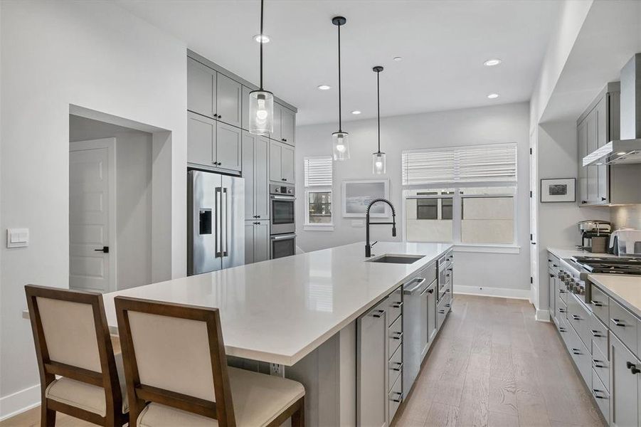 Sleek quartz countertops and a large island provide plenty of workspace for cooking and entertaining in the kitchen