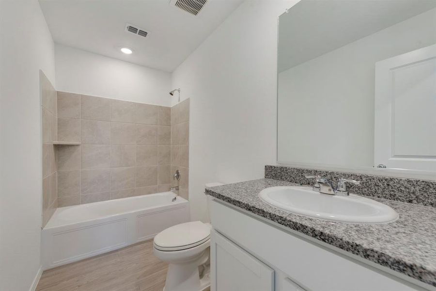 Full bathroom featuring hardwood / wood-style floors, toilet, vanity, and tiled shower / bath