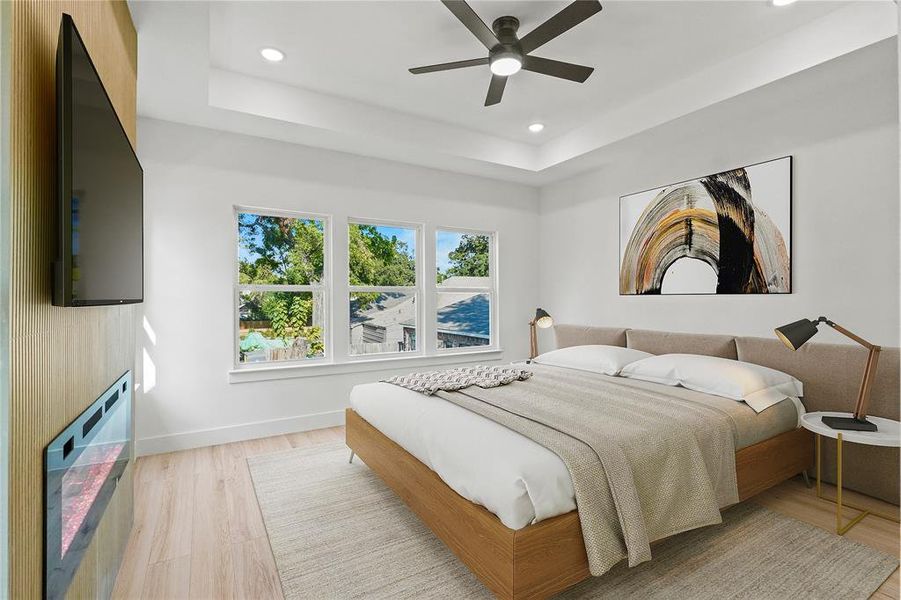 Bedroom with a raised ceiling, light wood-type flooring, and ceiling fan