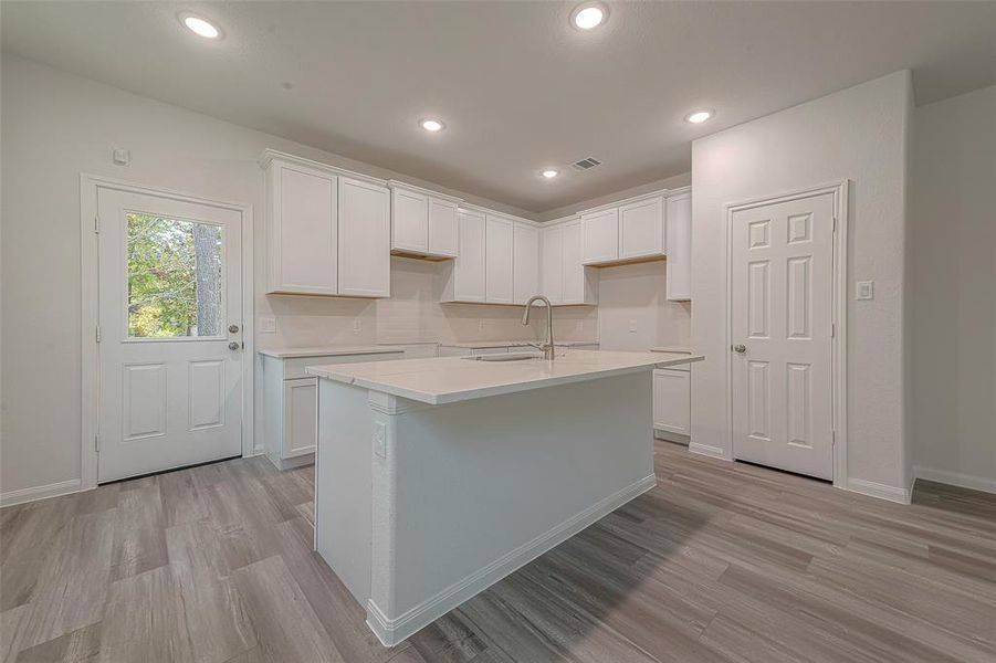The kitchen is a chef's dream with a gas range, granite countertops, tile backsplash, island, and dining area, all flowing seamlessly into the spacious living room.