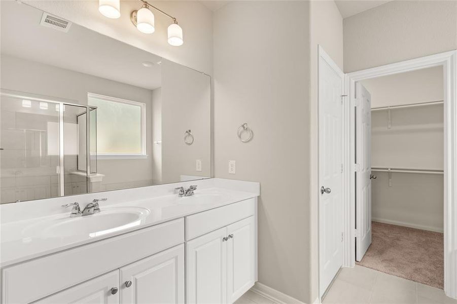 The en-suite bathroom offers a spa-like atmosphere with its elegant design, high end finishes, and tasteful lighting, creating a retreat within your own home.